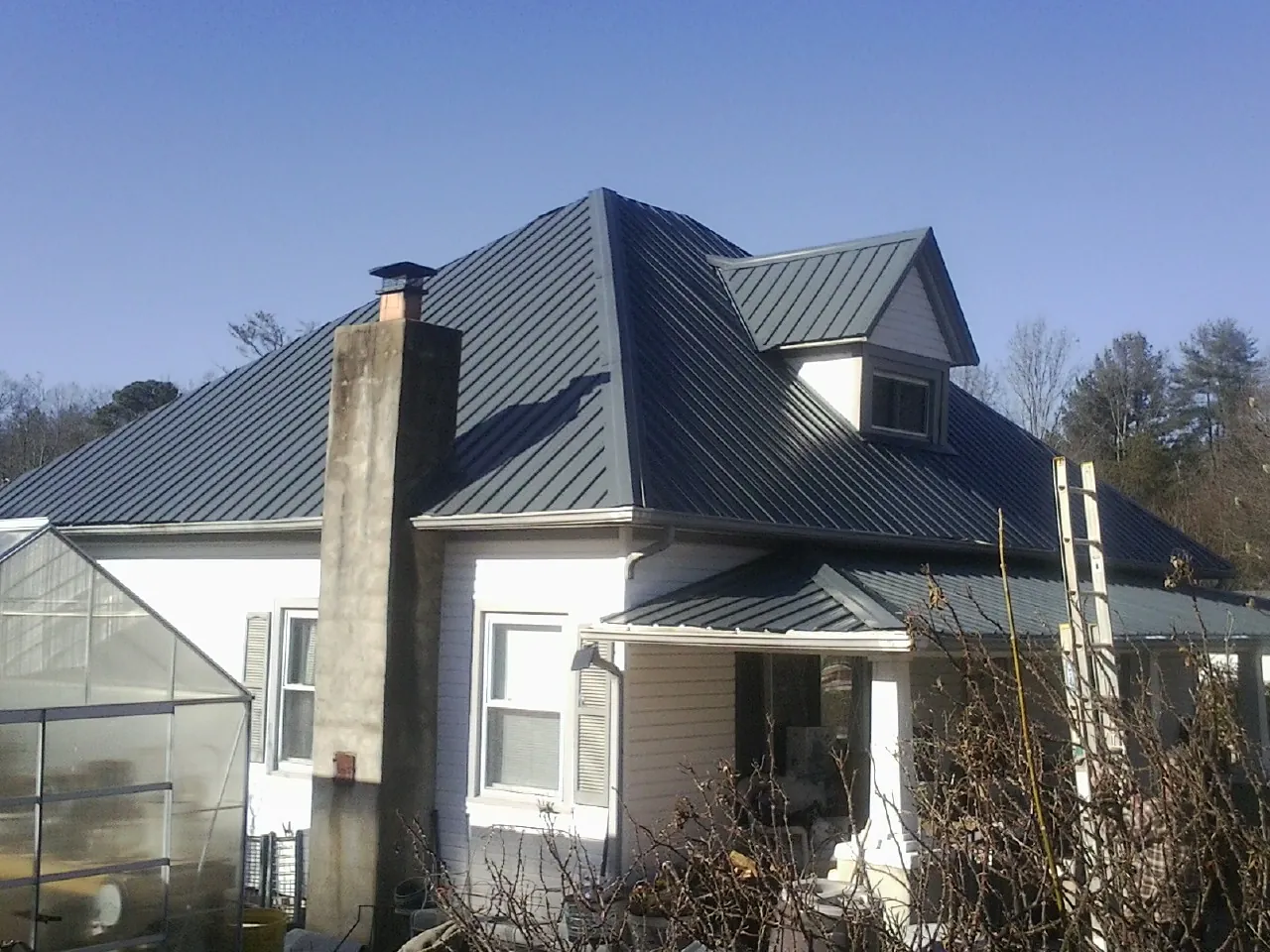 Dark blue standing seam metal roof on a white farmhouse with dormer — Slate & Tile Roof Repair by Roofing Brothers in East Thetford
