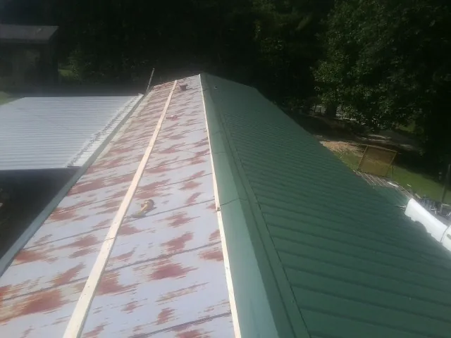 Old rusted panels beside newly installed green metal roofing — Wind Damage Roof Repair by Roofing Brothers in East Thetford