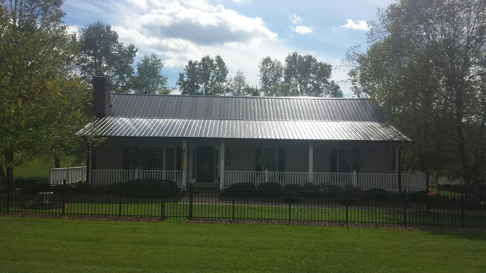 Gray metal roof on a brick ranch with a full width front porch — Gutter Guard Installation work by our crew in East Thetford