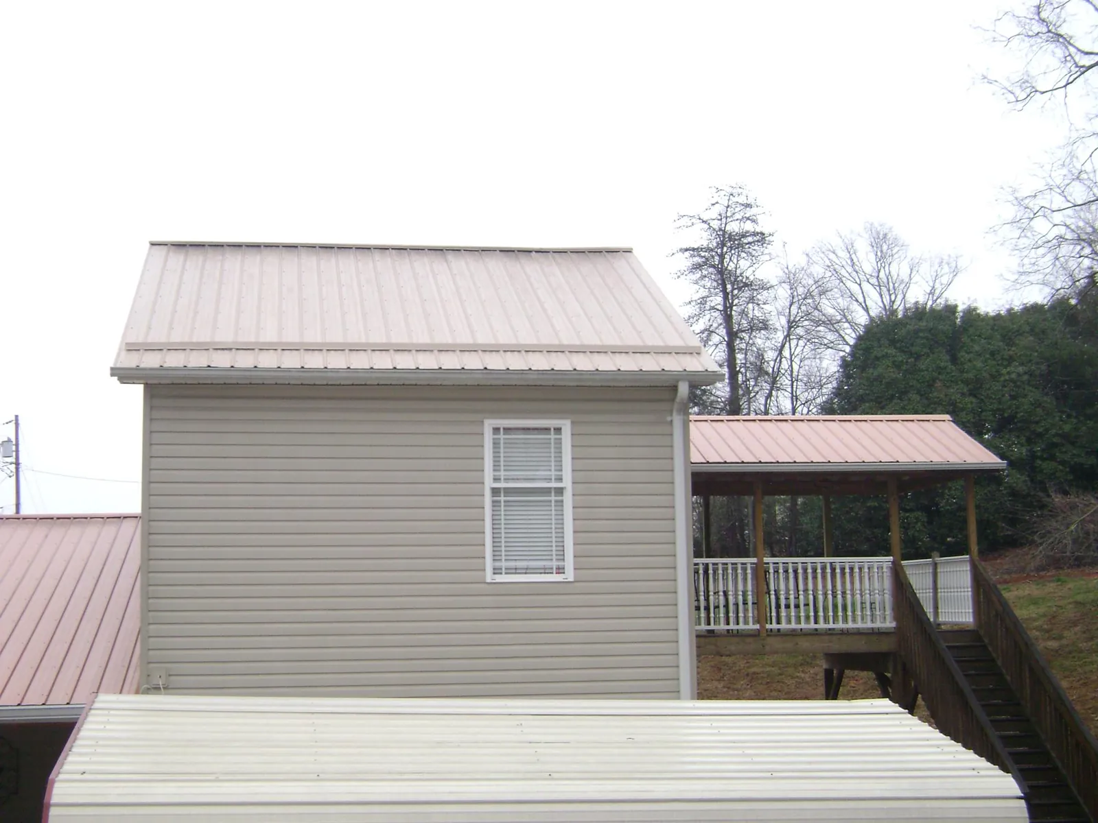 Tan metal roofs on a two story addition and attached porch, from a Roof Replacement job in East Thetford